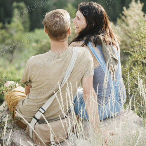A couple in the mountains, taking a break, sitting on a hillside. A couple in the mountains, taking a break, sitting on a hillside.