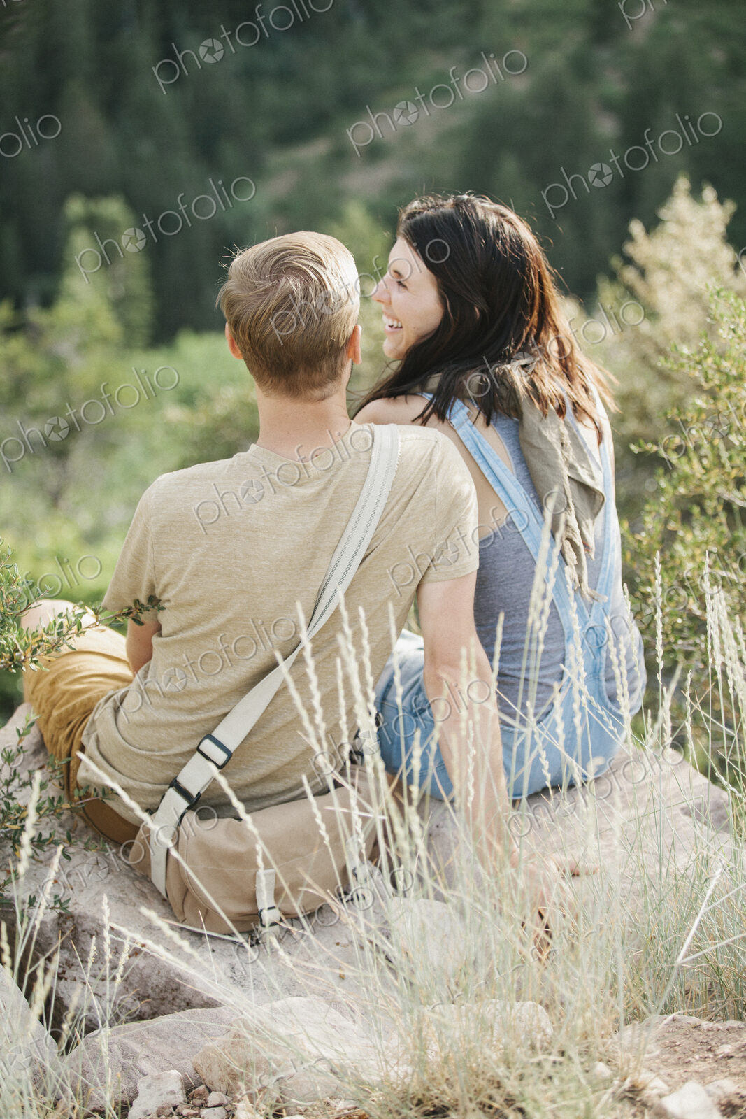 A couple in the mountains, taking a break, sitting on a hillside.
