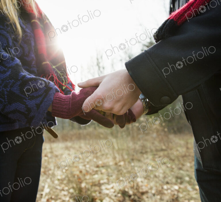 A couple in winter coats, outdoors on a winter's day. Holding hands.