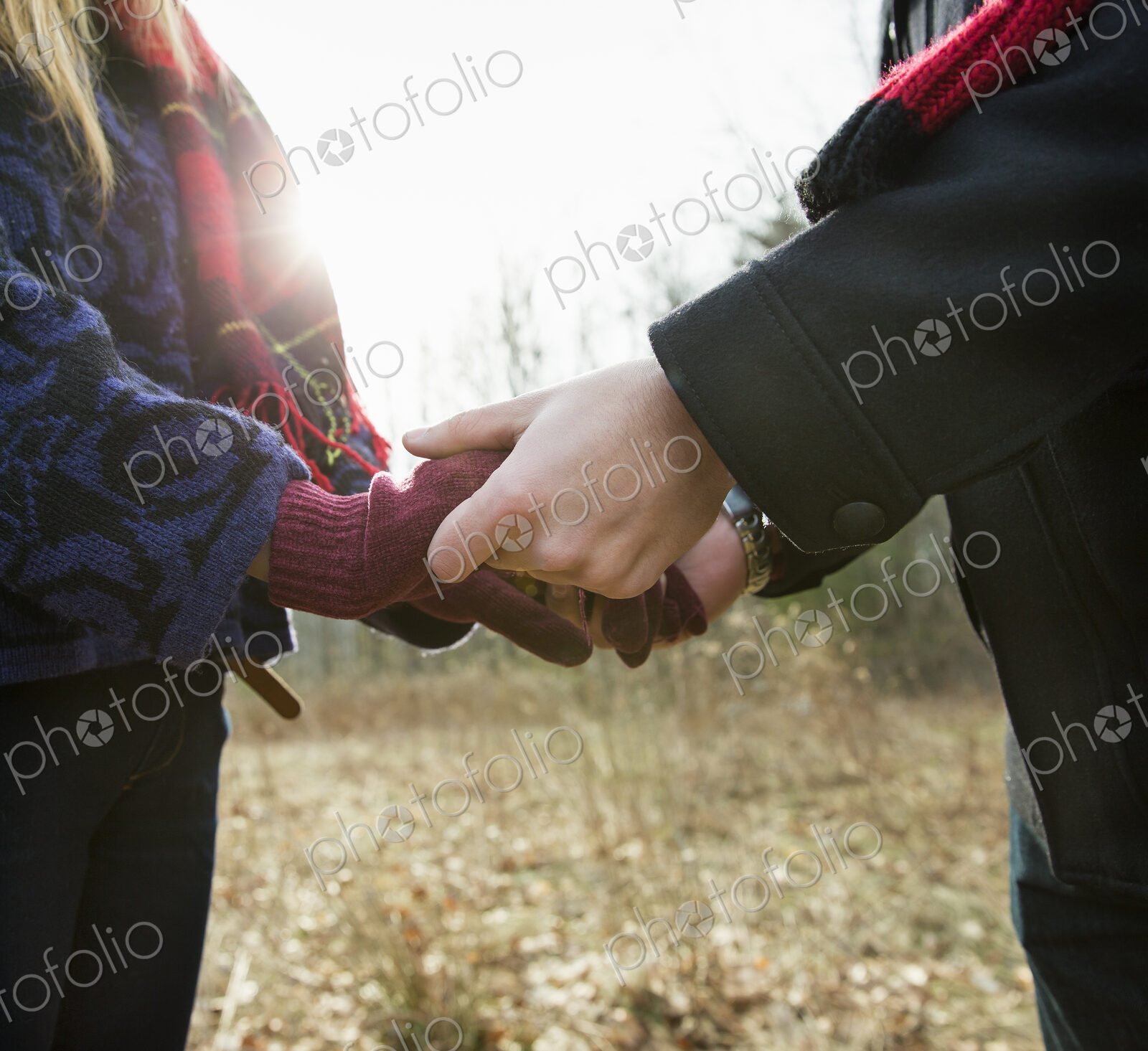 A couple in winter coats, outdoors on a winter’s day. Holding hands.