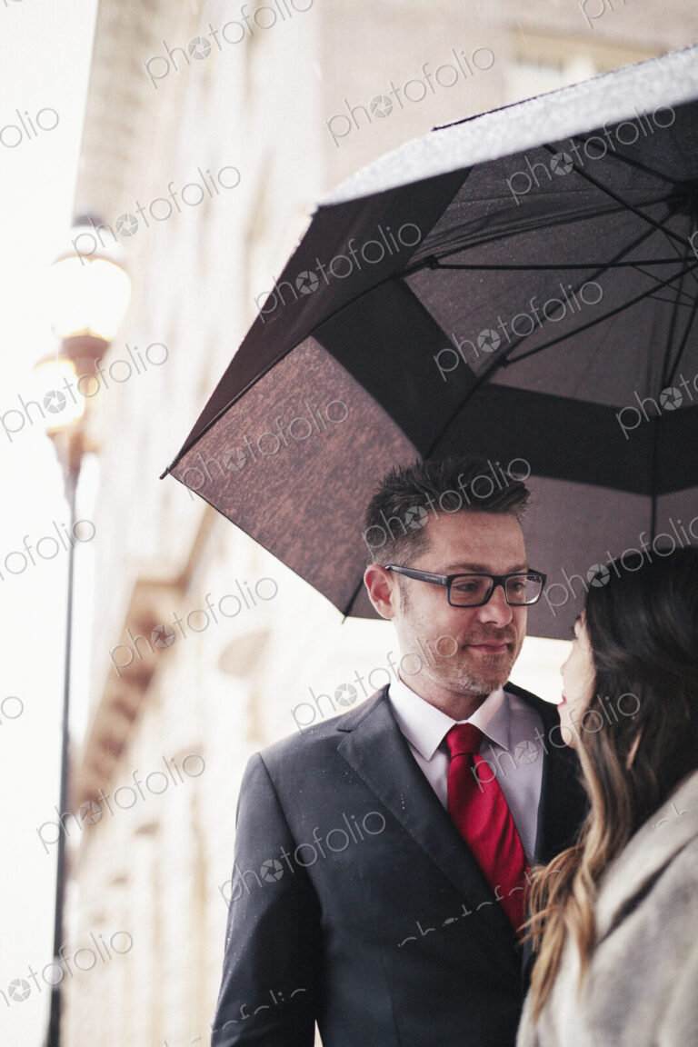 A couple, lovers in the city under an umbrella.