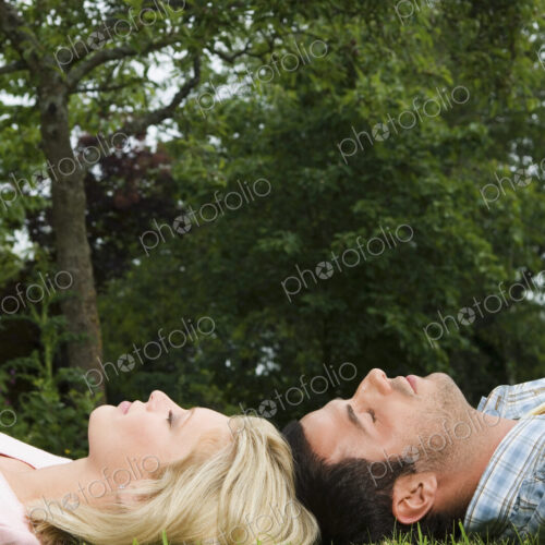 A couple lying on their backs, head touching on the grass, A couple lying on their backs, head touching on the grass,