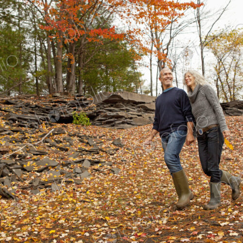 A couple, man and woman on a day out in autumn walking through fallen leaves. Holding… A couple, man and woman on a day out in autumn walking through fallen leaves. Holding…