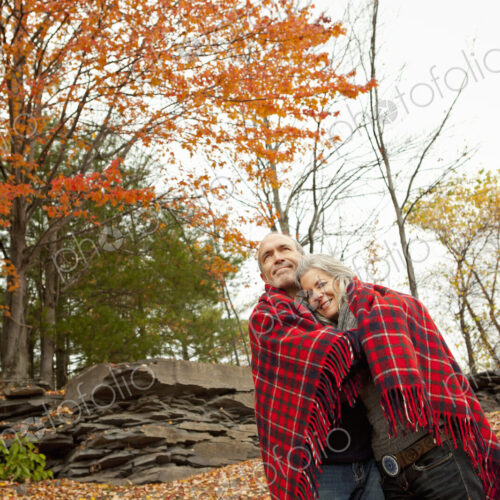 A couple, man and woman on a day out in autumn. Sharing a picnic rug to keep warm. A couple, man and woman on a day out in autumn. Sharing a picnic rug to keep warm.