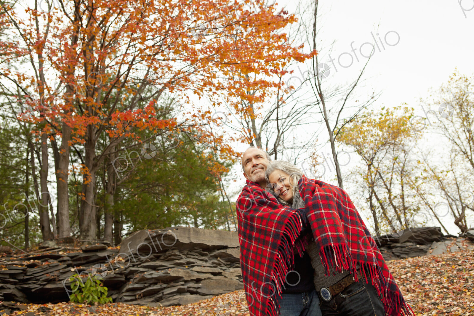 A couple, man and woman on a day out in autumn. Sharing a picnic rug to keep warm.