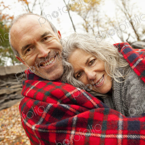 A couple, man and woman on a day out in autumn. Sharing a picnic rug to keep warm. A couple, man and woman on a day out in autumn. Sharing a picnic rug to keep warm.