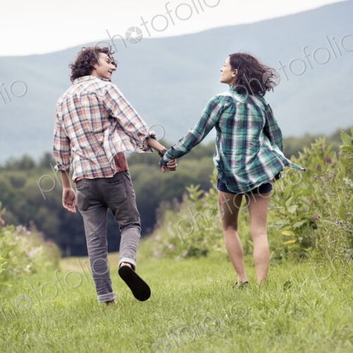 A couple, man and woman running through a meadow hand in hand. A couple, man and woman running through a meadow hand in hand.