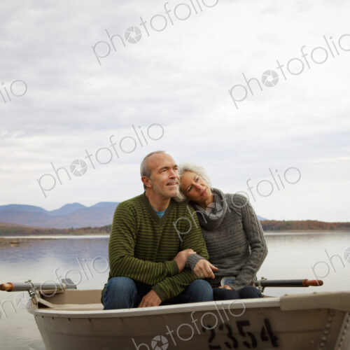 A couple, man and woman sitting in a rowing boat on the water on an autumn day. A couple, man and woman sitting in a rowing boat on the water on an autumn day.