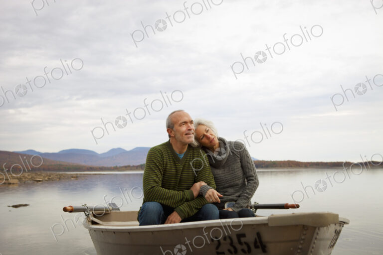 A couple, man and woman sitting in a rowing boat on the water on an autumn day.