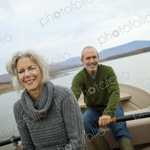 A couple, man and woman sitting in a rowing boat on the water on an autumn day.