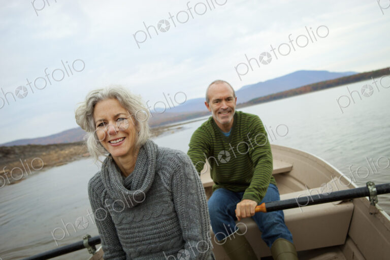 A couple, man and woman sitting in a rowing boat on the water on an autumn day.