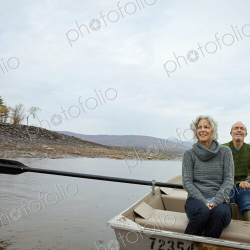 A couple, man and woman sitting in a rowing boat on the water on an autumn day.