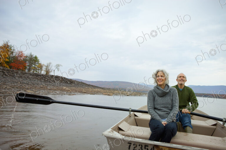 A couple, man and woman sitting in a rowing boat on the water on an autumn day.