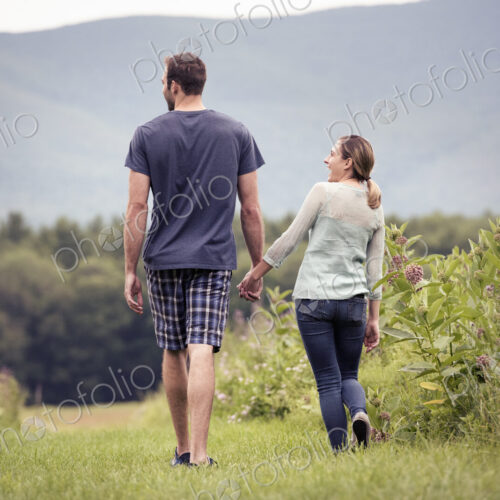 A couple, man and woman walking through a meadow holding hands. A couple, man and woman walking through a meadow holding hands.