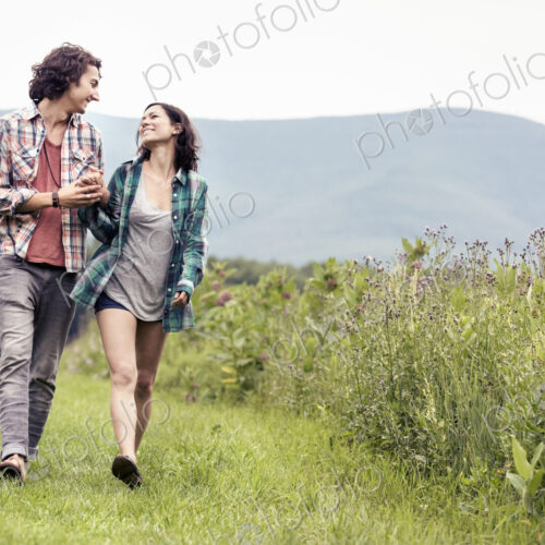 A couple, man and woman walking through a meadow in the countryside. A couple, man and woman walking through a meadow in the countryside.