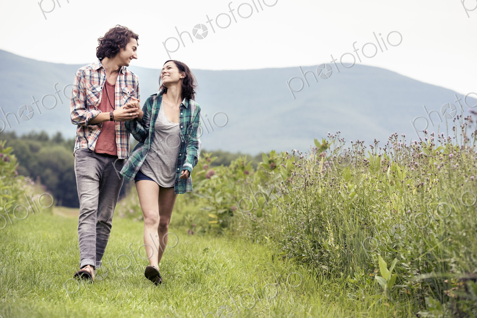 A couple, man and woman walking through a meadow in the countryside.