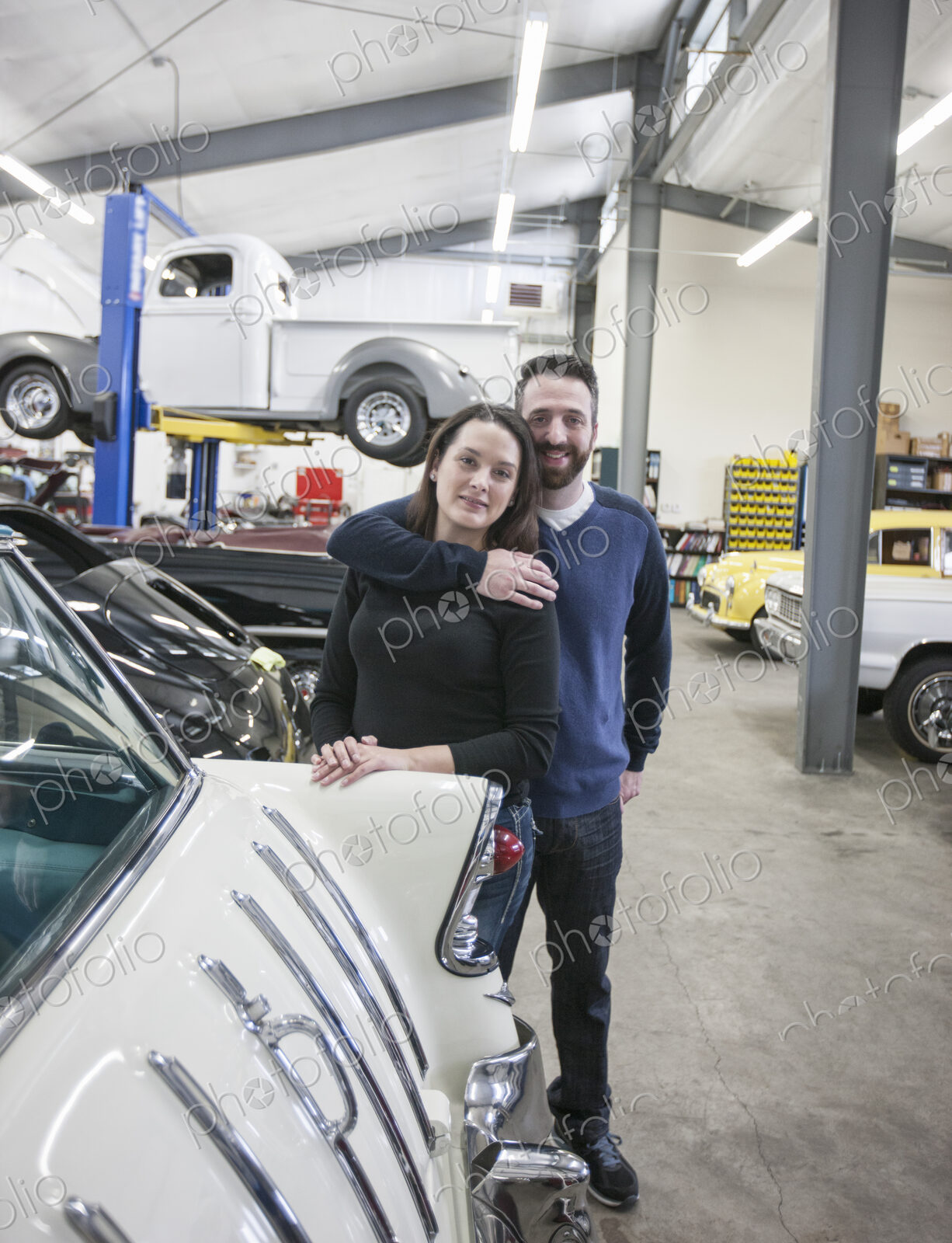 A couple, mechanics who work in a classic car auto repair shop. Man and woman.
