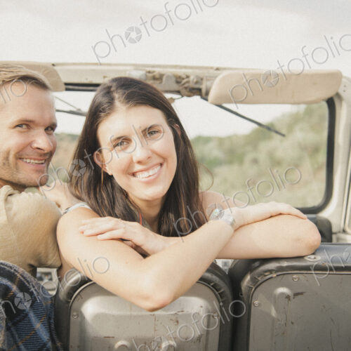 A couple on a road trip in a jeep side by side, a woman looking over her shoulder. A couple on a road trip in a jeep side by side, a woman looking over her shoulder.