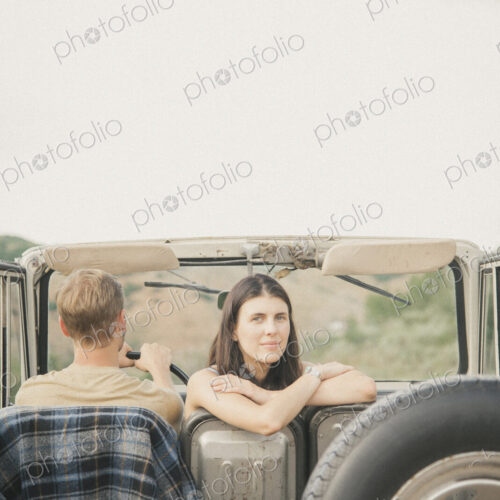 A couple on a road trip in a jeep side by side, a woman looking over her shoulder. A couple on a road trip in a jeep side by side, a woman looking over her shoulder.