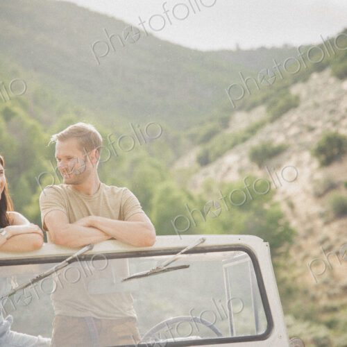 A couple on a road trip in the mountains standing side by side in a jeep looking around. A couple on a road trip in the mountains standing side by side in a jeep looking around.