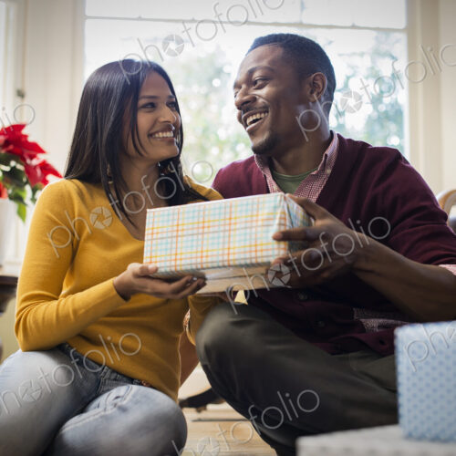 A couple on a sofa, exchanging wrapped presents. A couple on a sofa, exchanging wrapped presents.