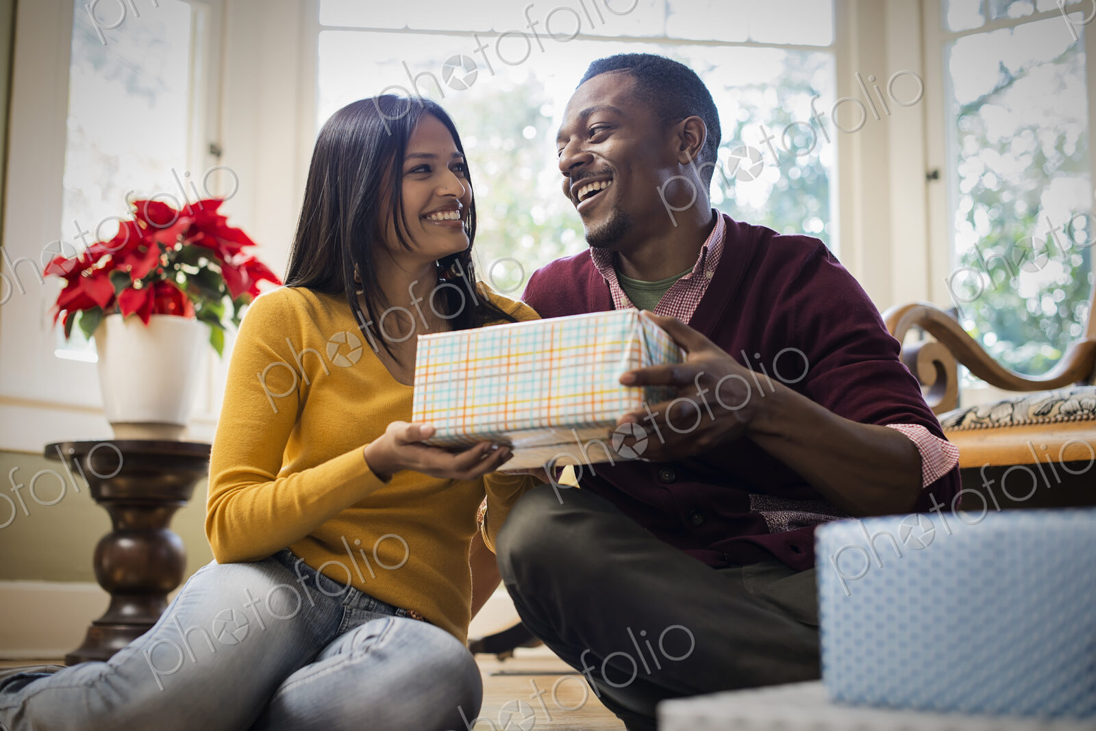A couple on a sofa, exchanging wrapped presents.
