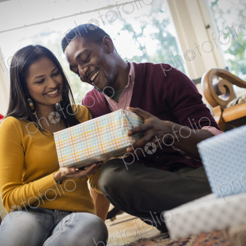 A couple on a sofa, exchanging wrapped presents. A couple on a sofa, exchanging wrapped presents.