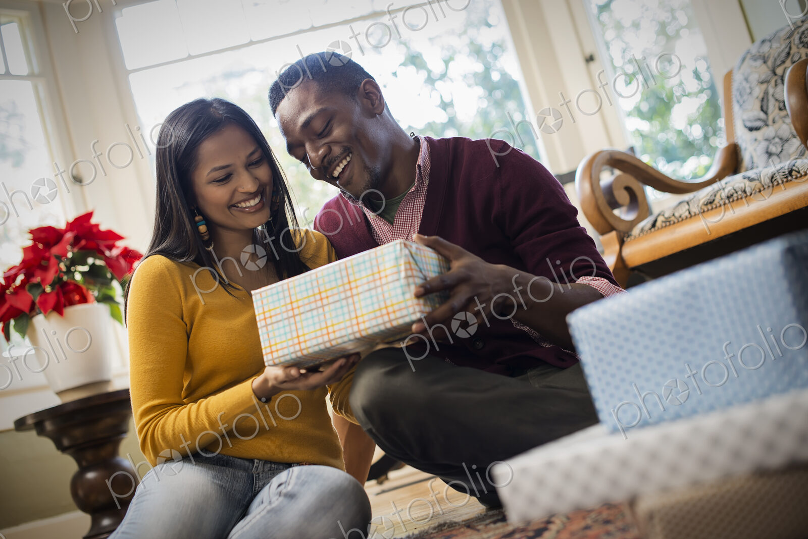 A couple on a sofa, exchanging wrapped presents.