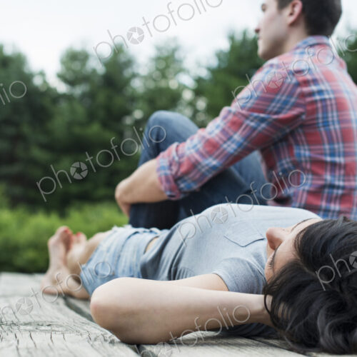 A couple relaxing on a jetty overlooking a mountain lake.