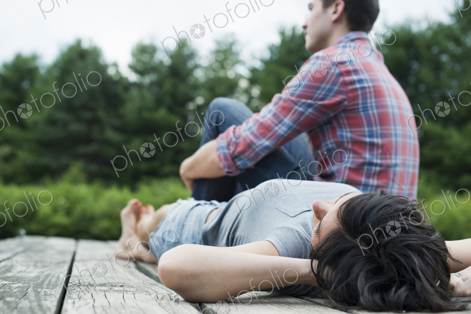 A couple relaxing on a jetty overlooking a mountain lake.