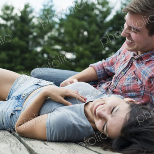 A couple relaxing on a jetty overlooking a mountain lake.