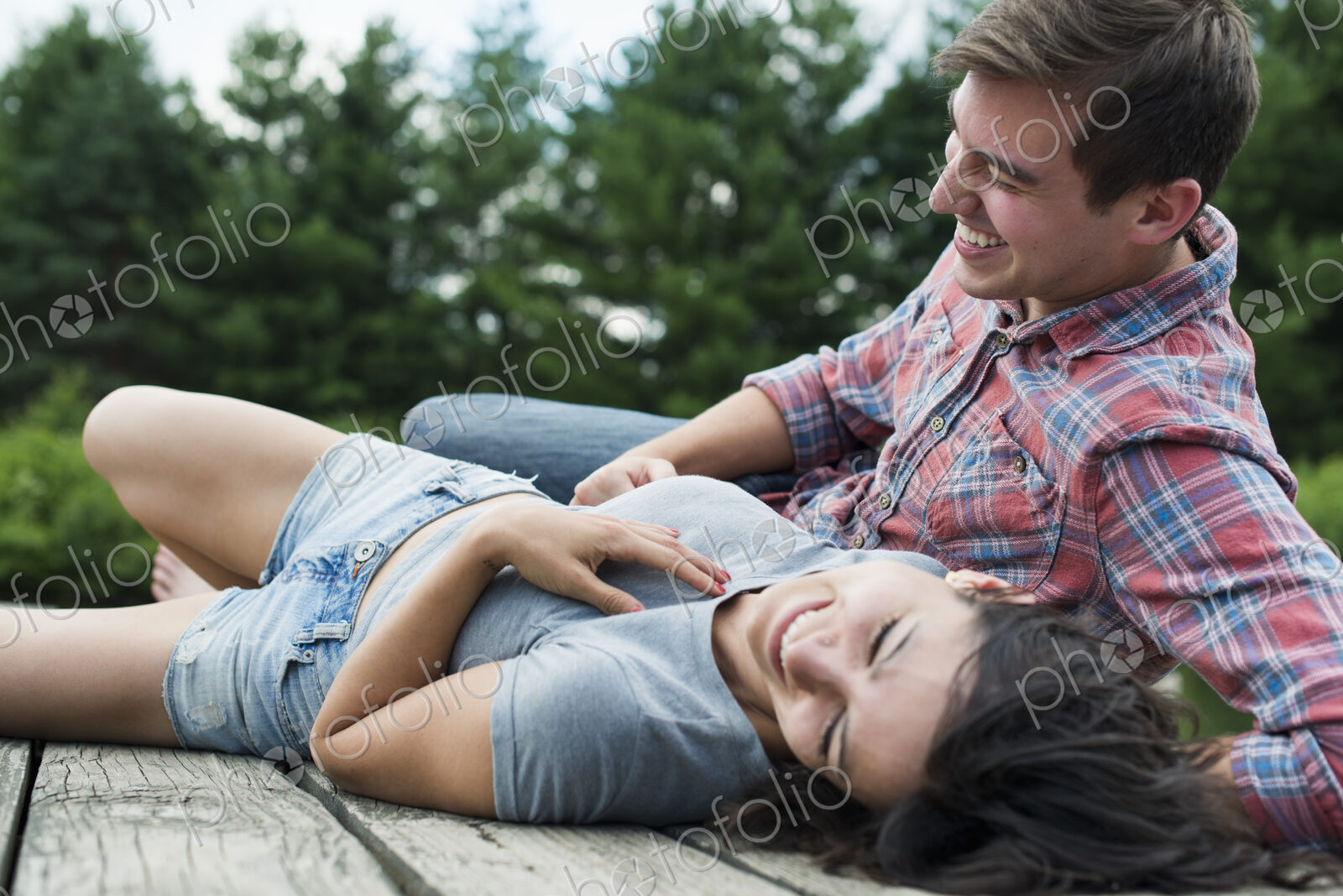 A couple relaxing on a jetty overlooking a mountain lake.
