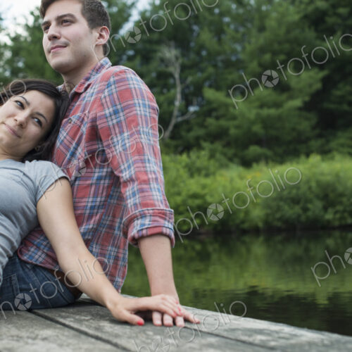 A couple relaxing on a jetty overlooking a mountain lake. A couple relaxing on a jetty overlooking a mountain lake.