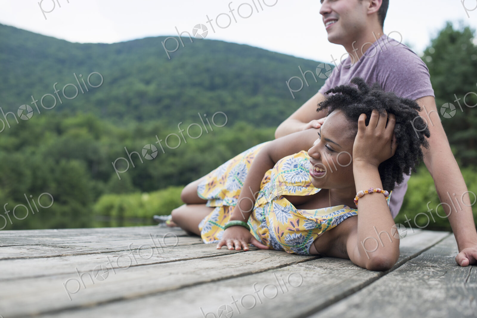 A couple relaxing on a jetty overlooking a mountain lake.