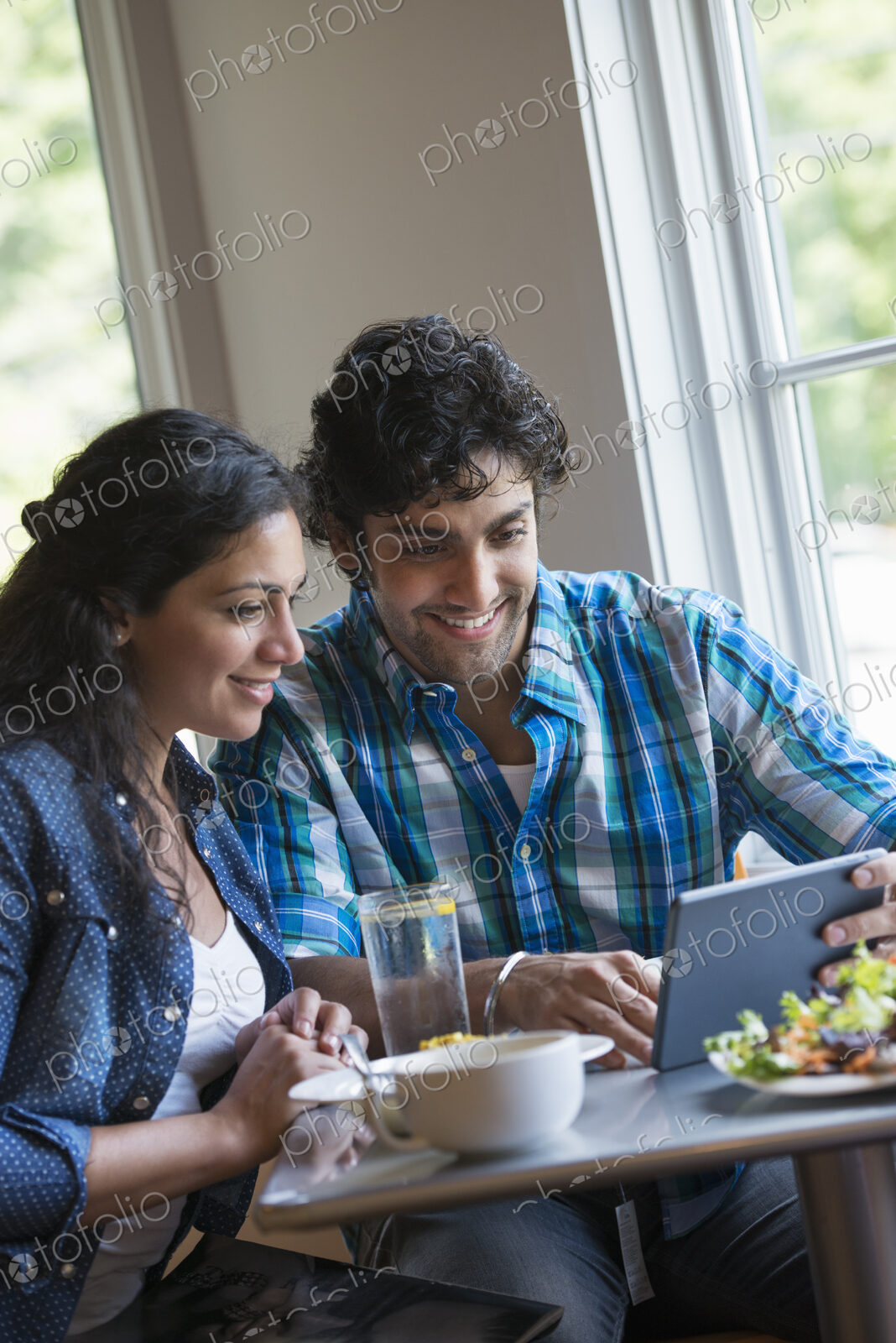 A couple seated looking at a digital tablet.