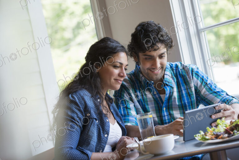 A couple seated looking at a digital tablet.