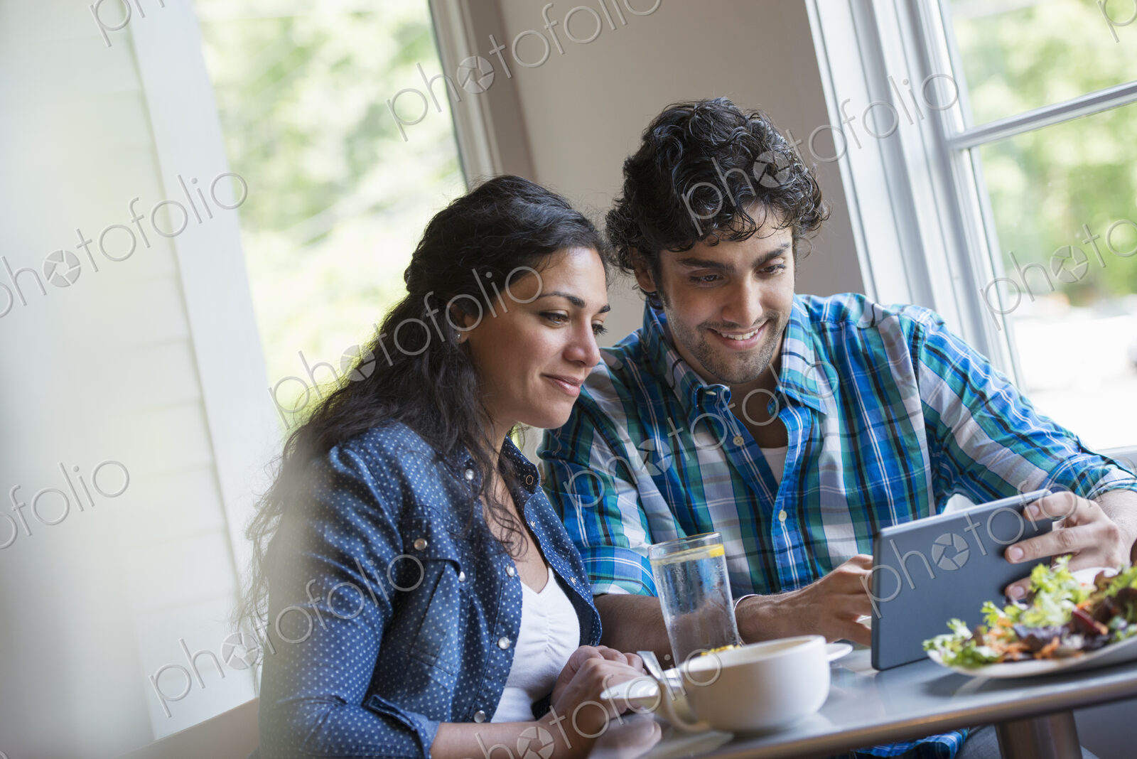 A couple seated looking at a digital tablet.