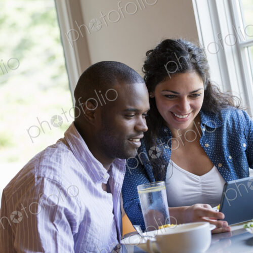 A couple seated looking at a digital tablet. A couple seated looking at a digital tablet.