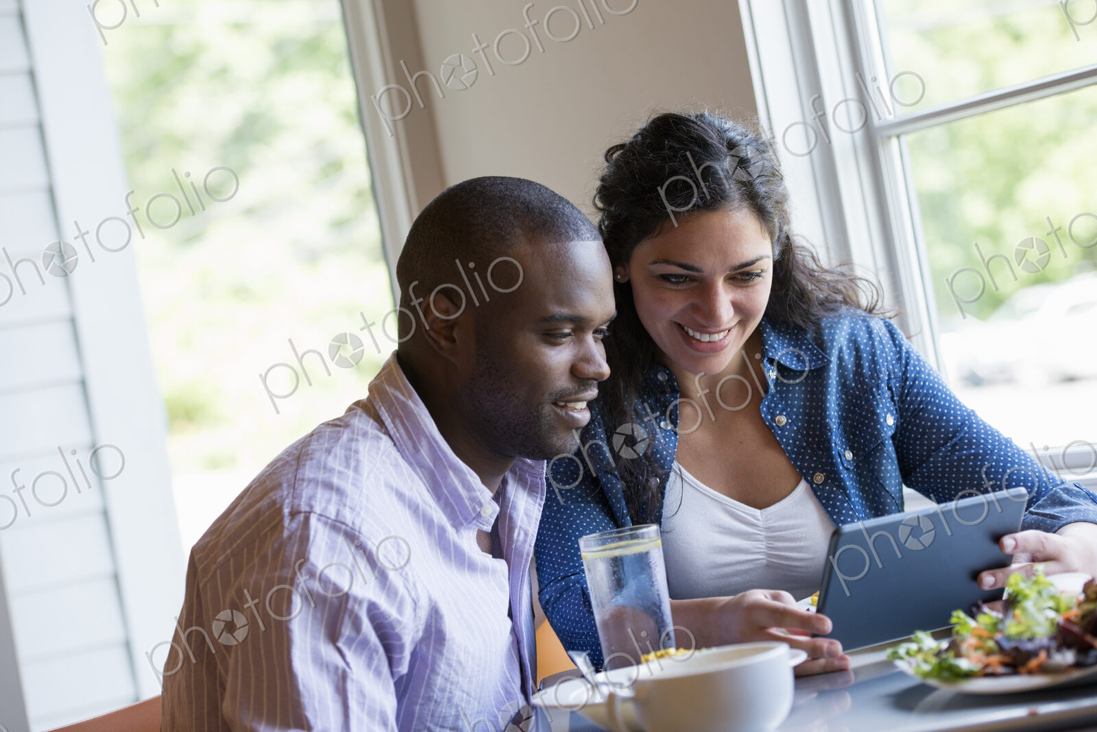 A couple seated looking at a digital tablet.