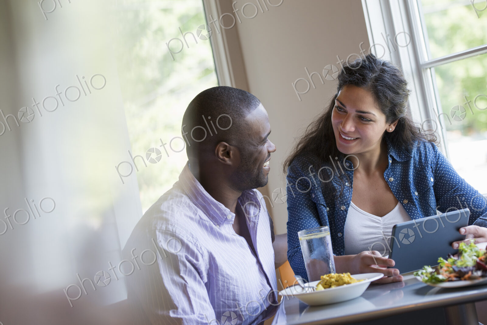 A couple seated looking at a digital tablet.
