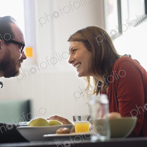 A couple sitting in a coffeeshop over breakfast. Leaning towards each other. A couple sitting in a coffeeshop over breakfast. Leaning towards each other.
