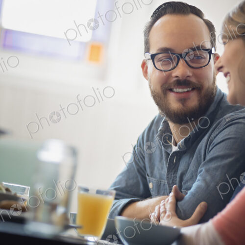 A couple sitting in a coffeeshop smiling and talking over a cup of coffee. A couple sitting in a coffeeshop smiling and talking over a cup of coffee.