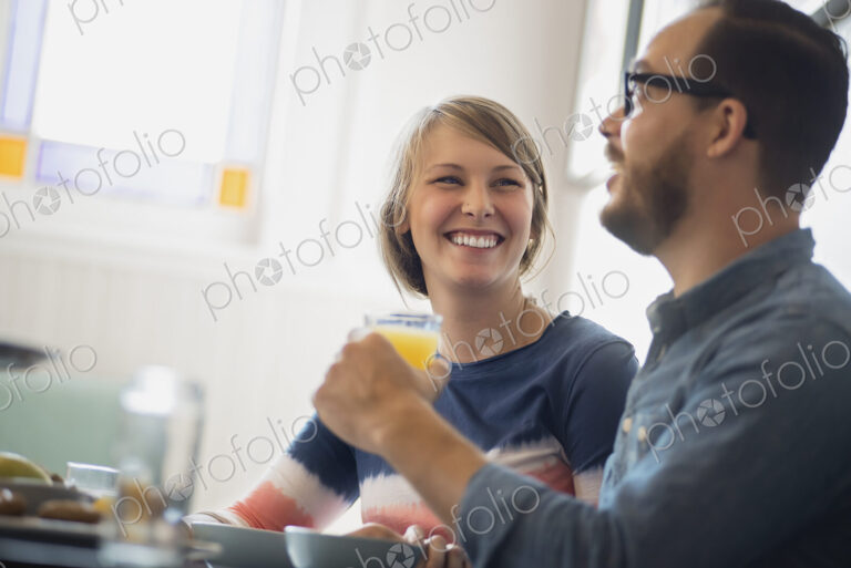 A couple sitting in a coffeeshop smiling and talking over a cup of coffee.