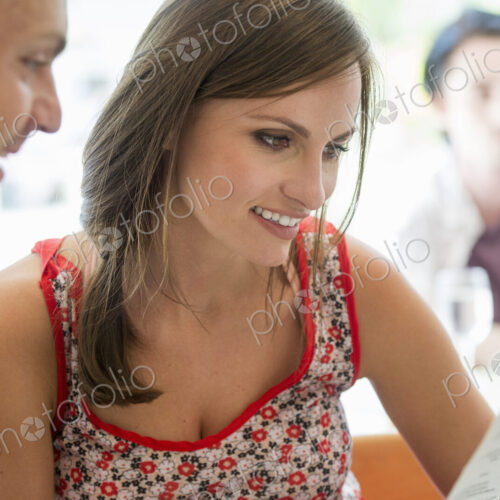 A couple sitting in a restaurant looking at a menu. A couple sitting in a restaurant looking at a menu.