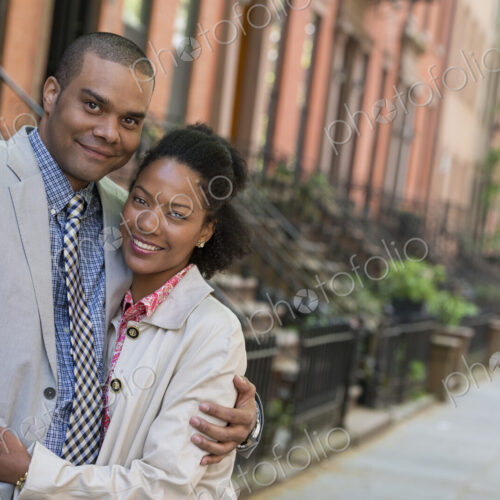 A couple standing side by side on a city street.