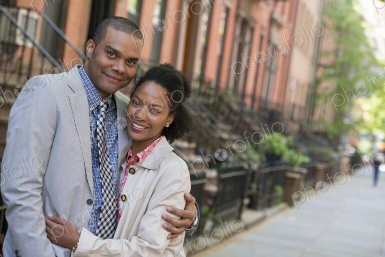 A couple standing side by side on a city street.