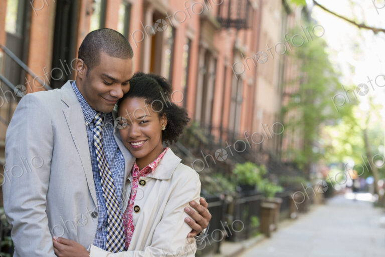 A couple standing side by side on a city street.