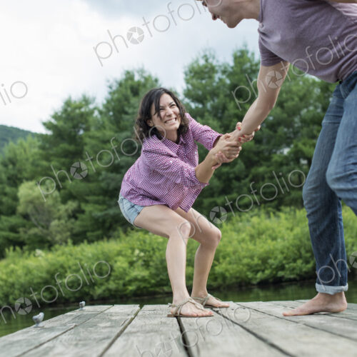 A couple trying to pull each other into the water off a jetty