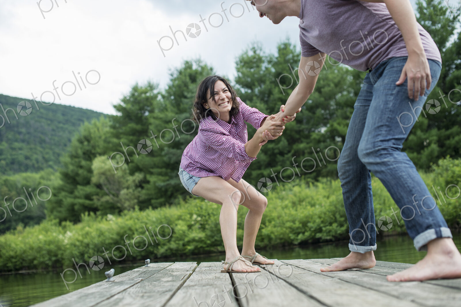 A couple trying to pull each other into the water off a jetty