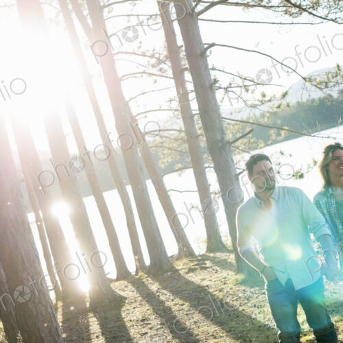 A couple walking in woodland on the shores of a lake. A couple walking in woodland on the shores of a lake.